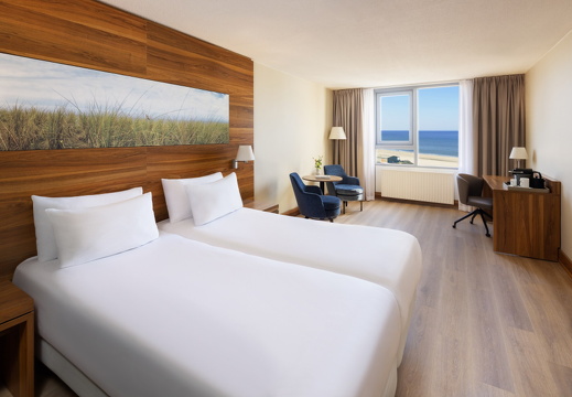 NH Zandvoort Rooms Standard Seaview Twin Bed Blue Chairs Curtains Open Flowers Desk Coffee Machine